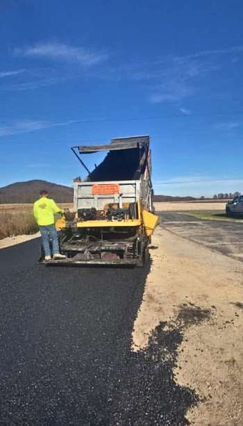 Aloners paving crew operating paver on rural road