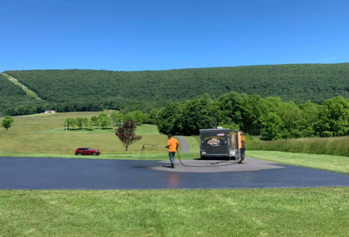 Aloners crew sealcoating rural driveway with mountain backdrop