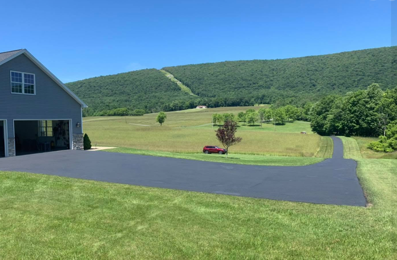 Freshly sealed winding driveway at rural home with mountain view