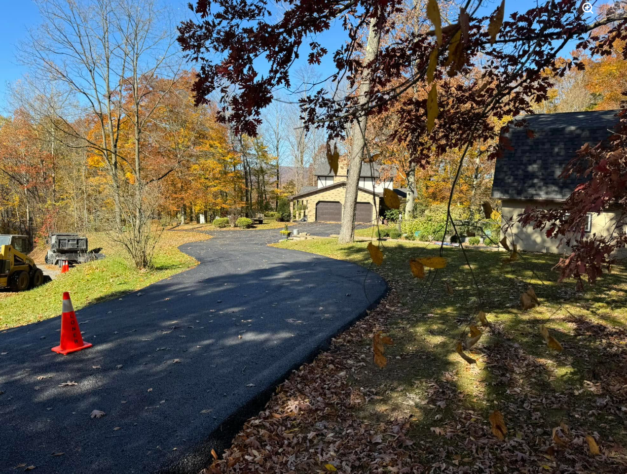 Freshly paved winding driveway at wooded home in autumn