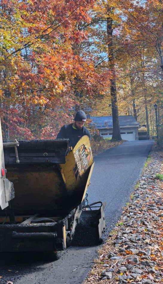 Aloners crew operating paver on residential driveway in autumn
