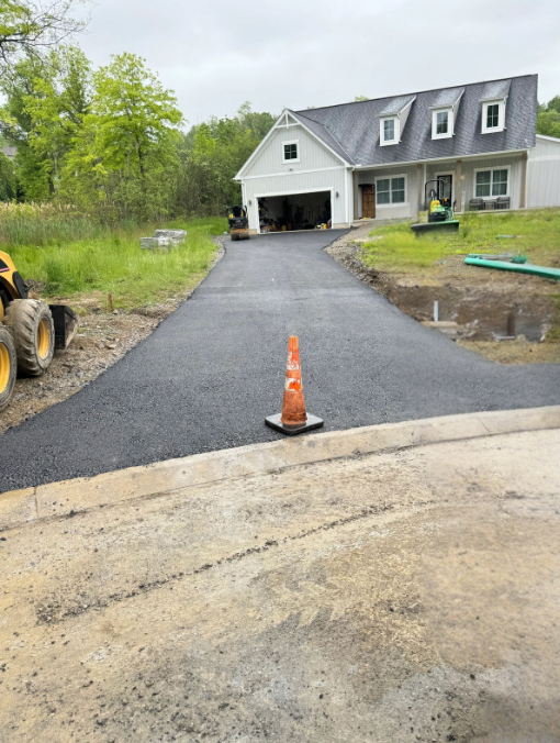New asphalt driveway at modern farmhouse under construction