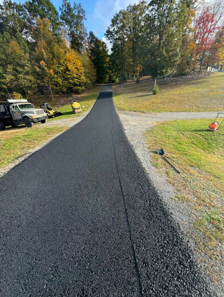 Freshly paved winding driveway with Aloners crew and equipment in autumn